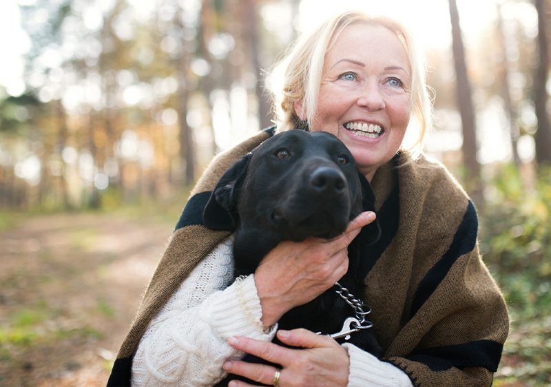 Portrait of happy senior woman with a dog in autumn nature 